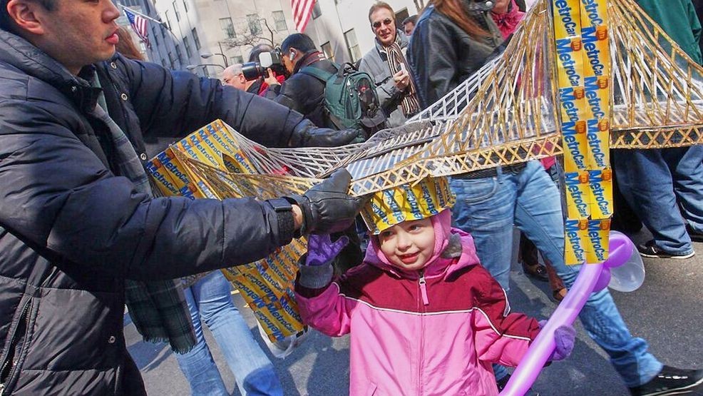FILE -  Russell Chin, left, helps Angie Hoyle, 3, of the Brooklyn borough of New York, as she tries on a hat made of MetroCards shaped as the Brooklyn Bridge during the Easter Parade on New York's Fifth Avenue, March 23, 2008. (AP Photo/Tina Fineberg, File)