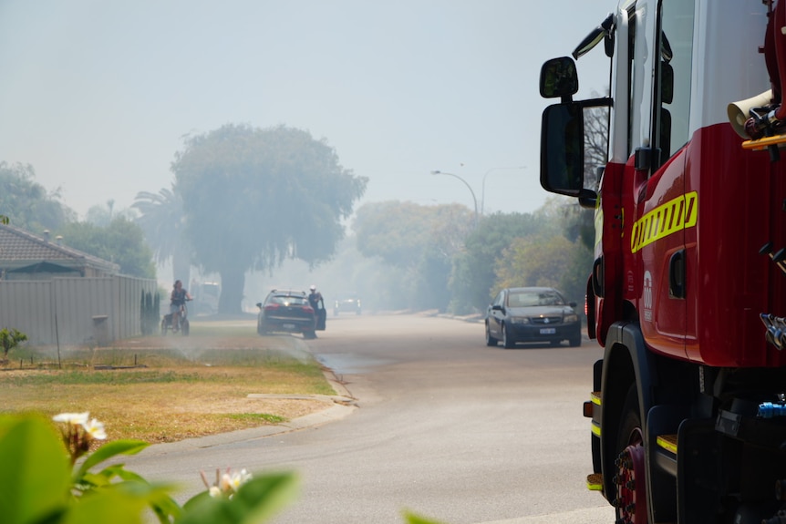 A fire truck is parked in a smokey street