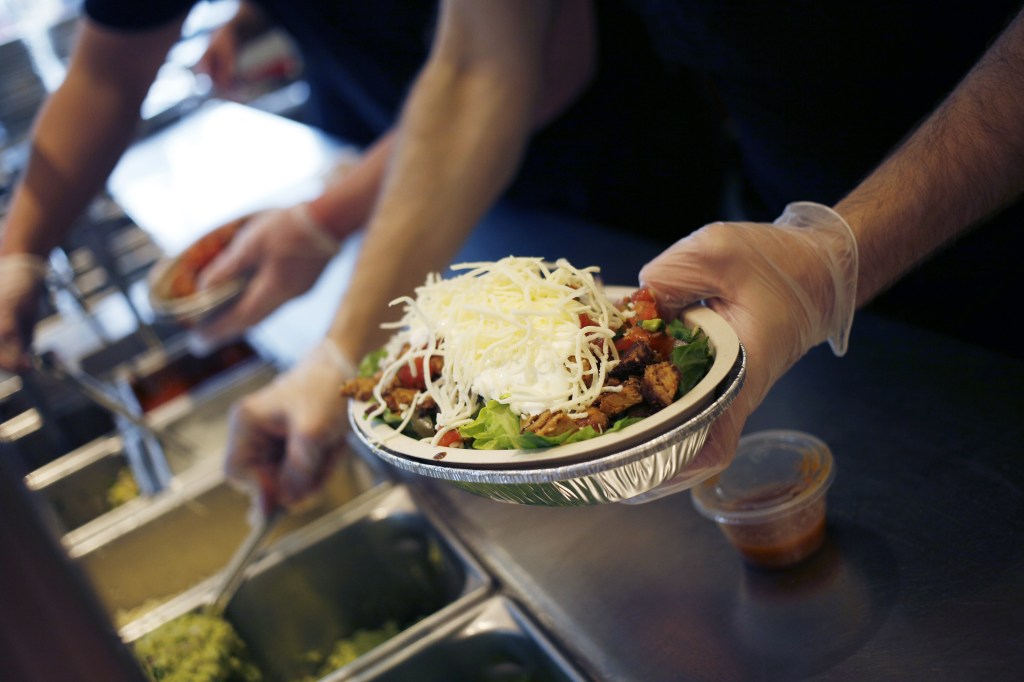 Employee prepares a Chipotle burrito bowl.