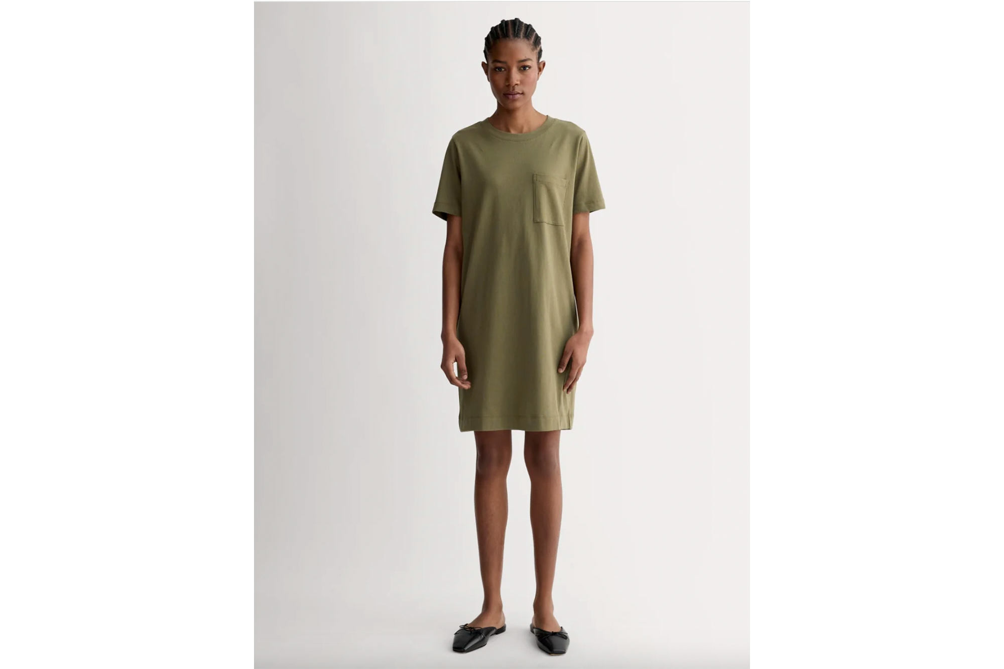 A woman modeling an olive green t-shirt dress with a front pocket.