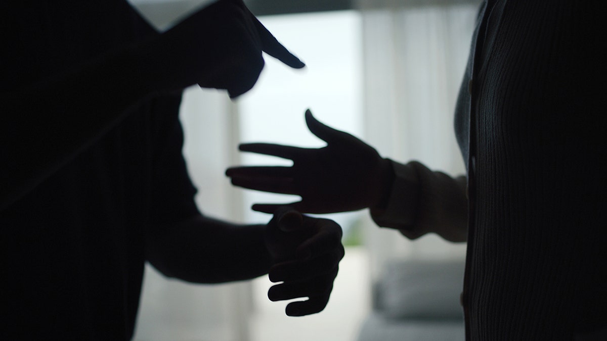 Silhouette image close-up of couple's hands as they agues, indicating family or relationship struggles.