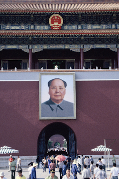 A tall wall in China with a large portrait of a man