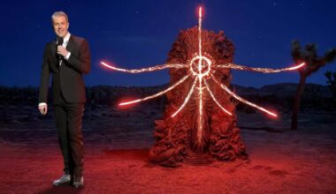 Geoff Keighley stands next to a demonic statue.