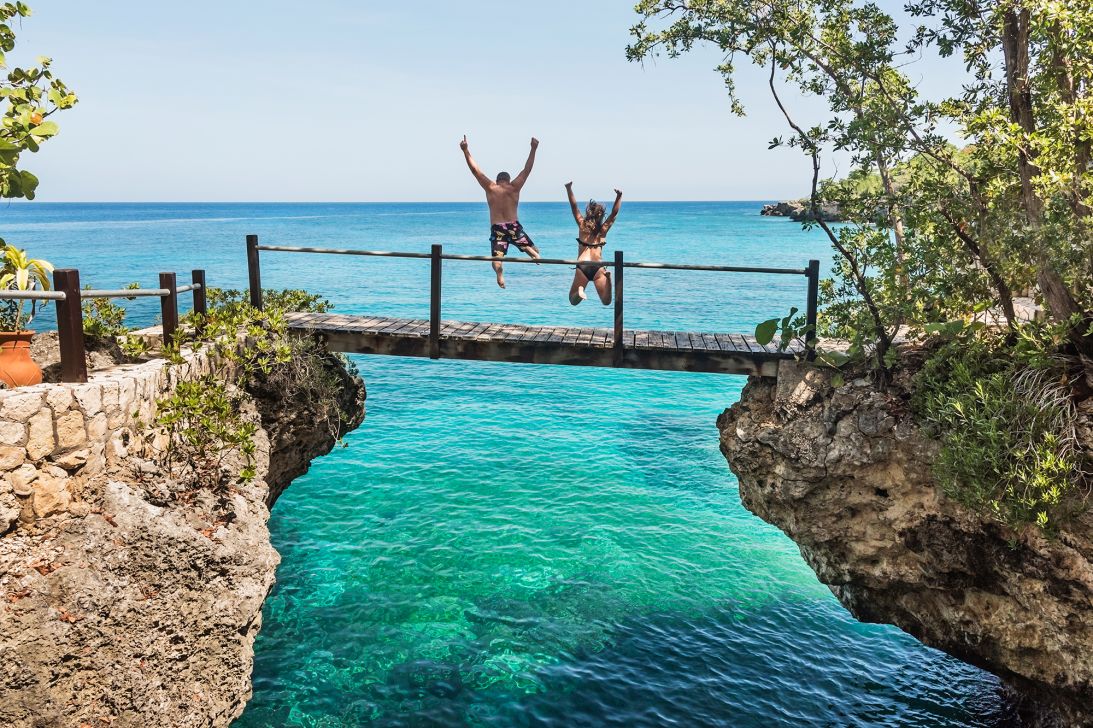 Two tourists jump into the ocean in Negril, Jamaica.