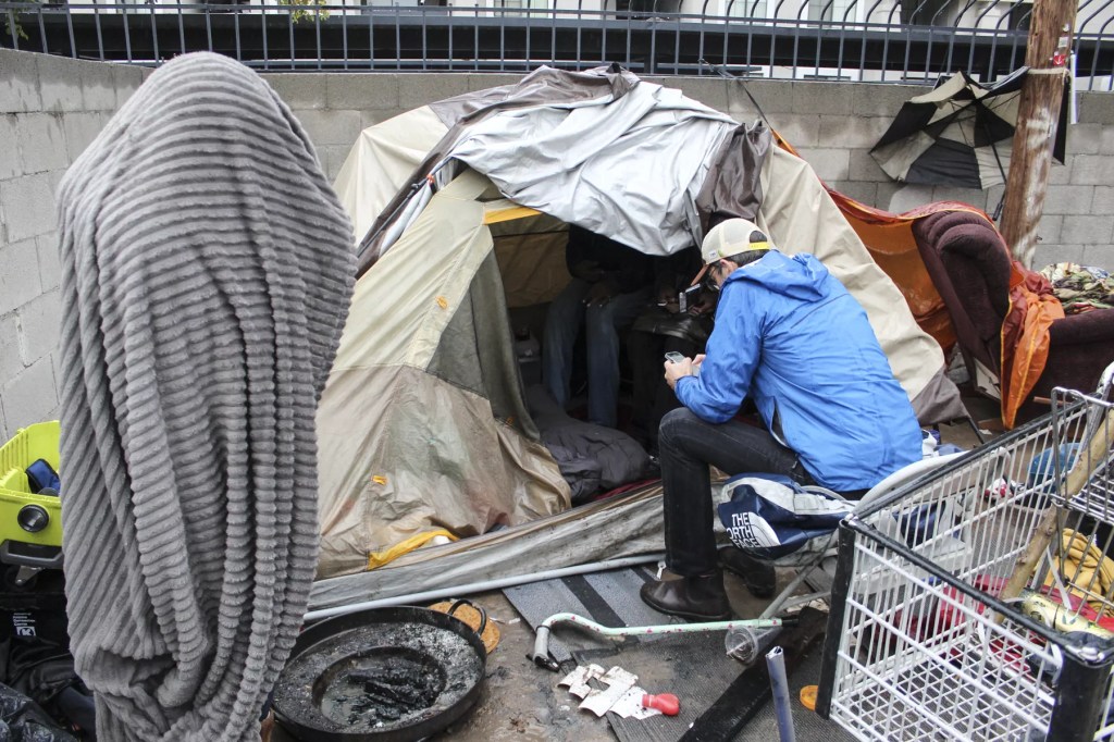 Brian Gruters talks to people living in a dirt lot.