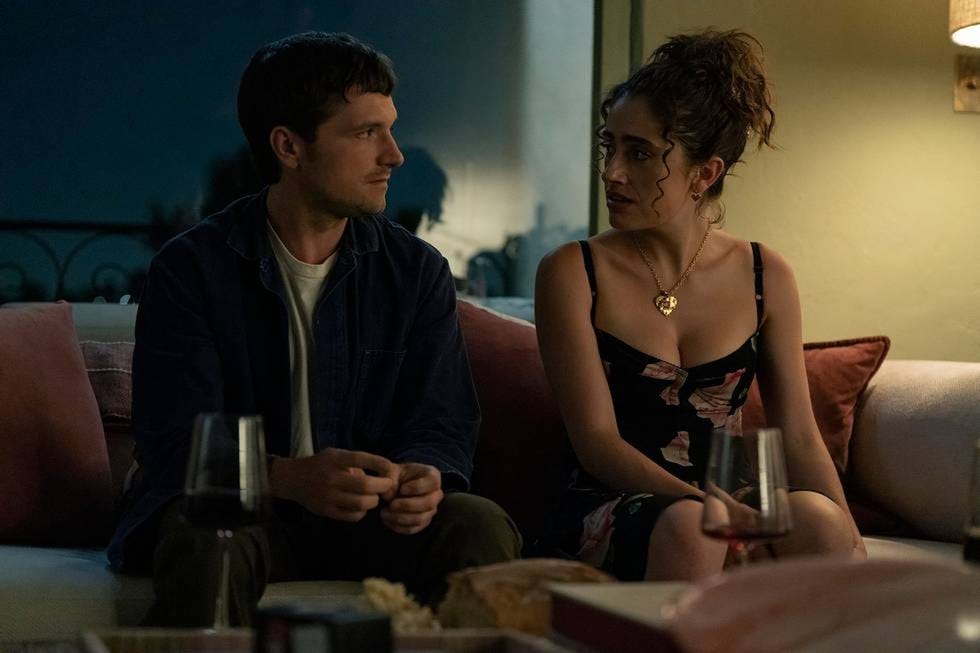 two individuals sitting on a couch in a dimly lit room