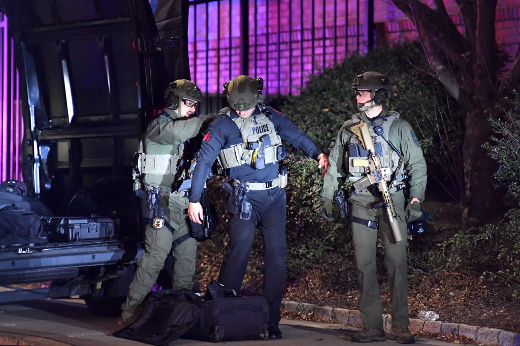 Law enforcement officials assist one another while putting on gear in a neighborhood near Brown University, Saturday, Dec. 13, 2025, in Providence, R.I. during the investigation of a shooting. 