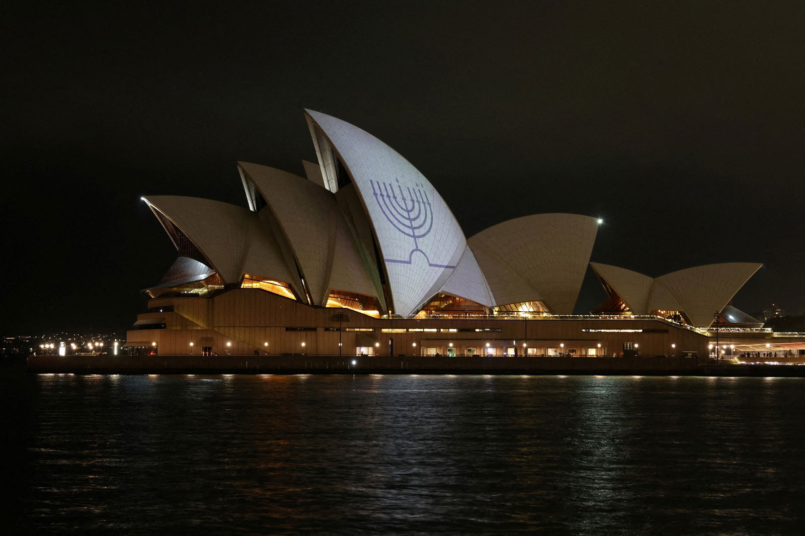 A white roof of the Sydney Opera House is lit up white with a blue menorah