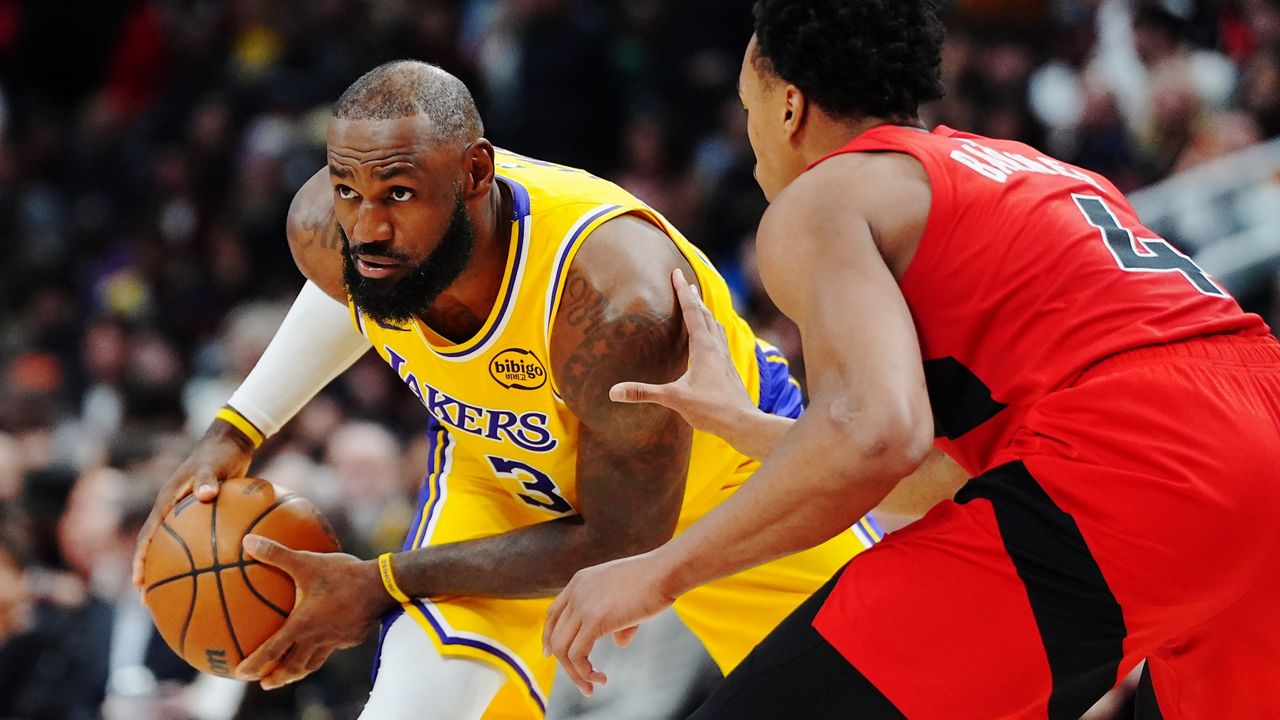 Los Angeles Lakers' LeBron James, left, is guarded by Toronto Raptors' Scottie Barnes (4) during second-half NBA basketball game action in Toronto, Thursday, Dec. 4, 2025. (Frank Gunn/The Canadian Press via AP)