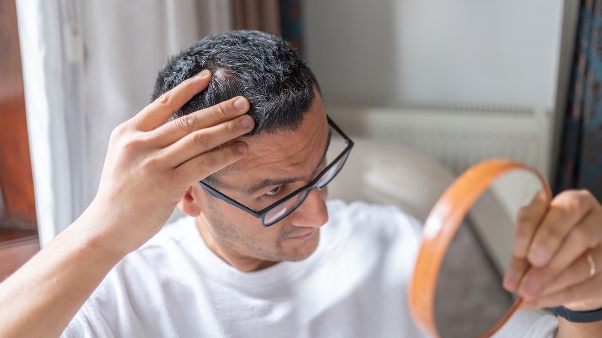 Man looking at hair in mirror