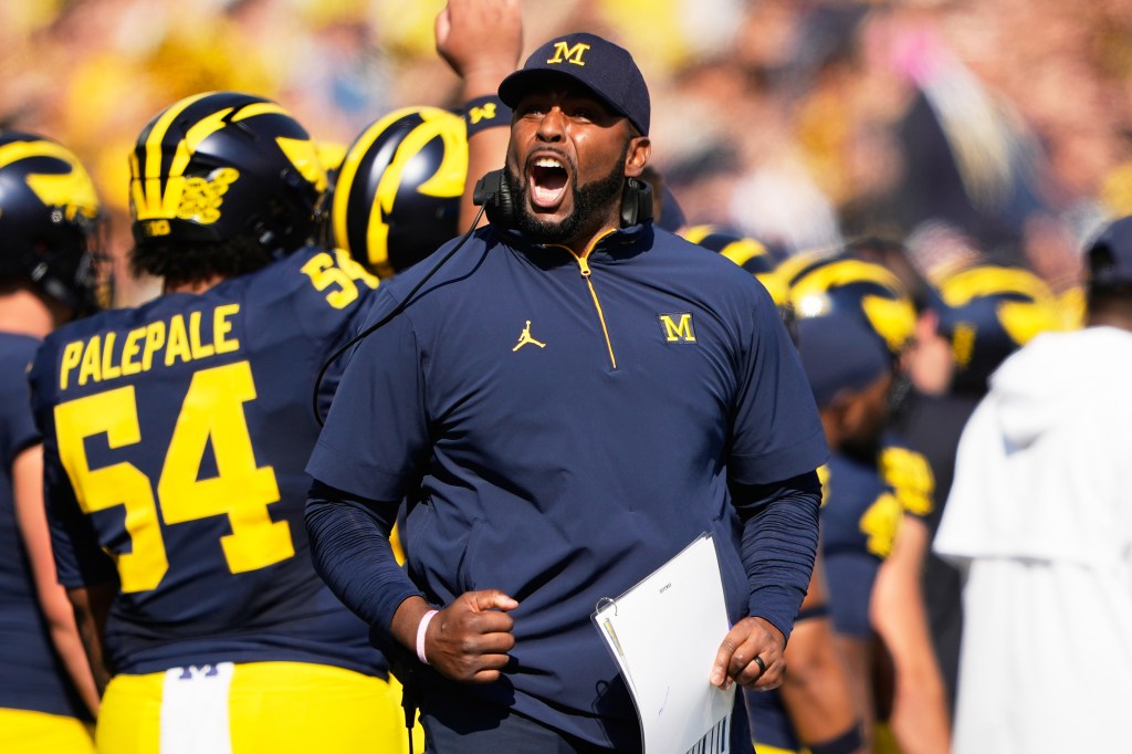 Michigan head coach Sherrone Moore shouting on the sideline during a game.