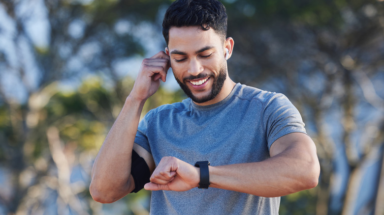 A man controls the music in his earbuds from a smartwatch