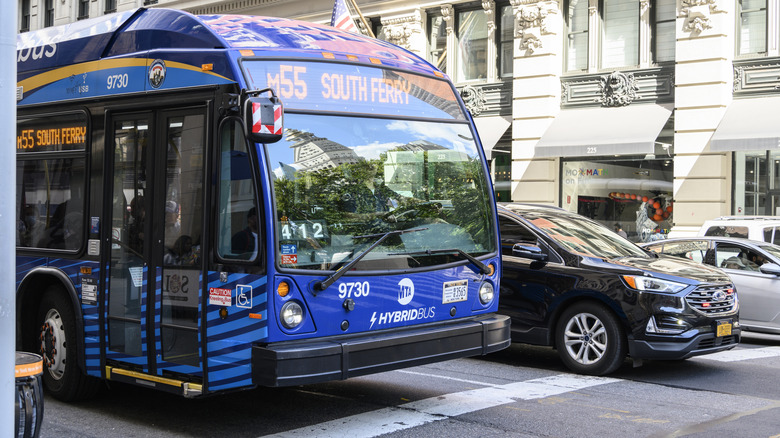 A number 55 MTA bus in New York City, black Ford Edge driving next to it