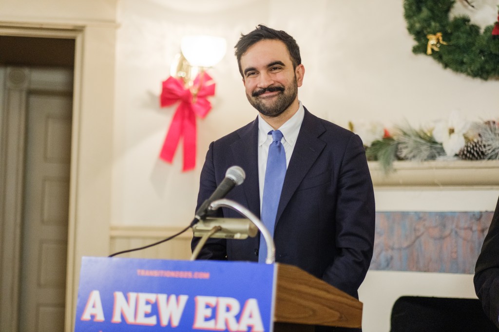 New York City Mayor-elect Zohran Mamdani smiling at a press conference.