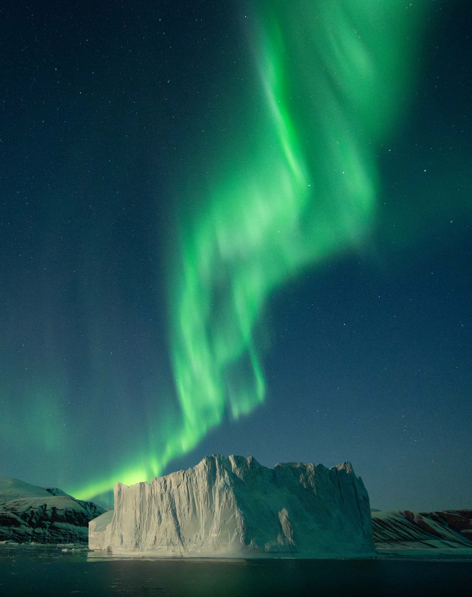 Green aurora borealis over an iceberg