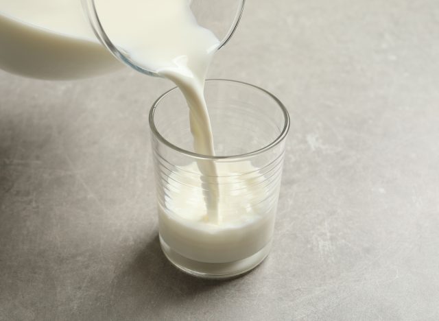 Pouring milk into glass on grey table