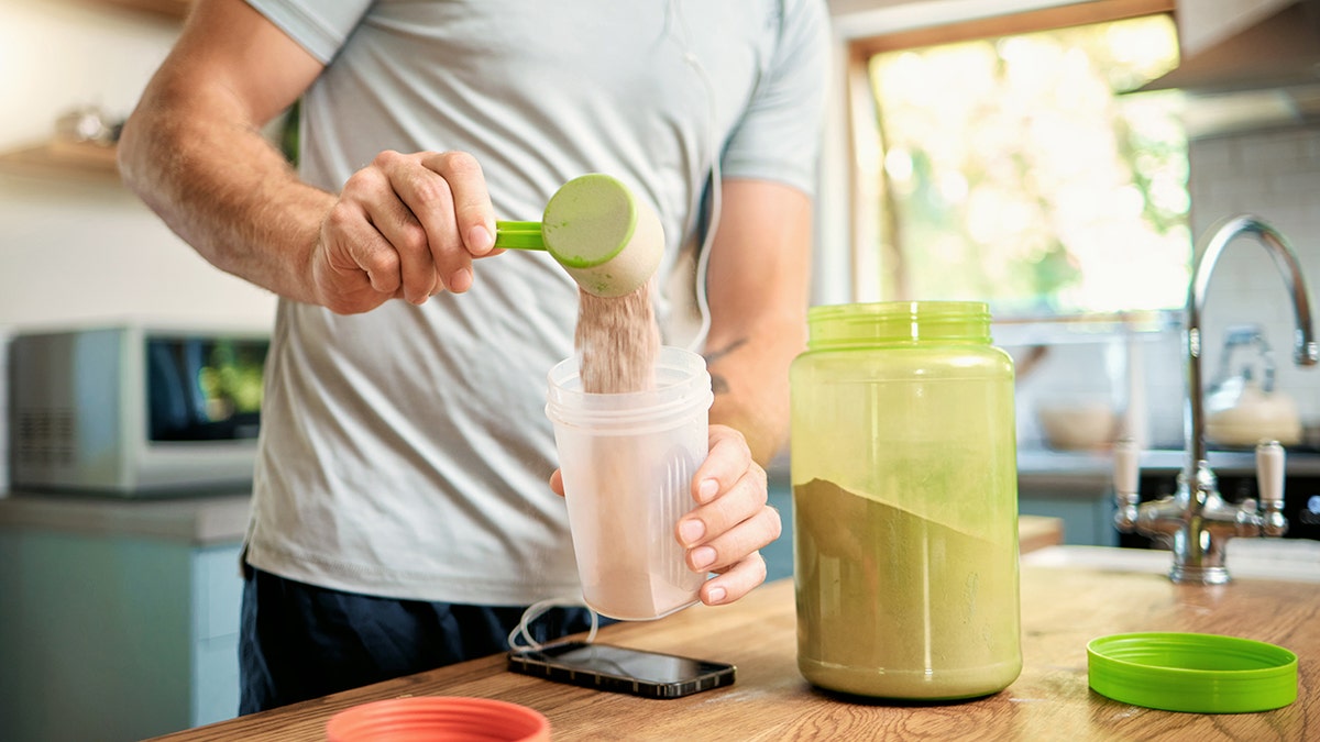 A man makes a protein shake in a small blender bottle as a supplement for muscle building and weight loss