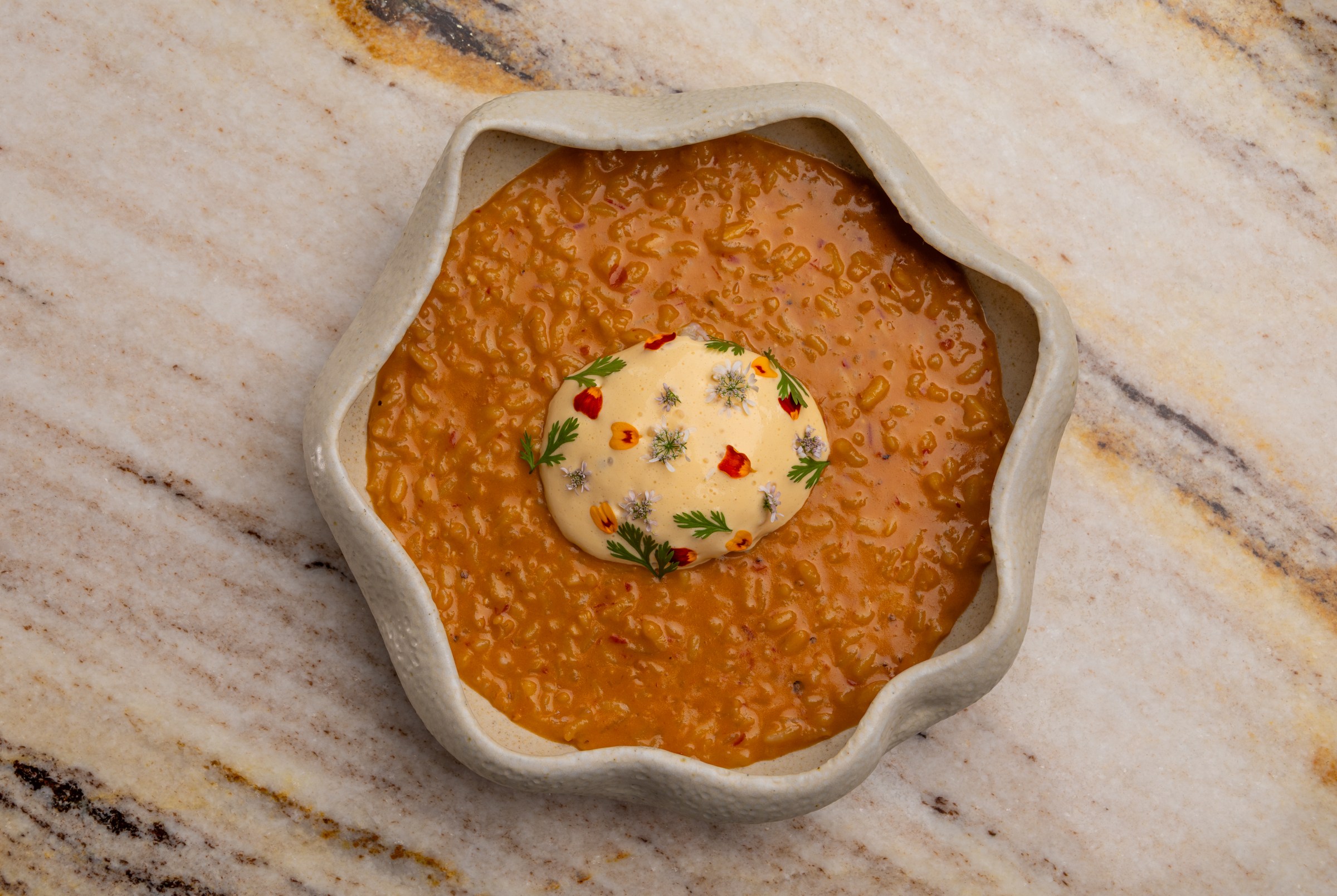 Overhead shot of rice porridge with chile and crab on a stone table in a wavy bowl at Vin Folk.