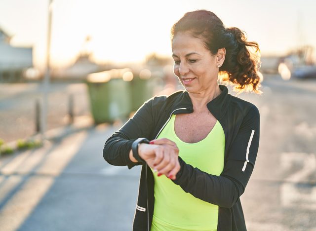 Middle age hispanic woman working out with smart watch outdoors