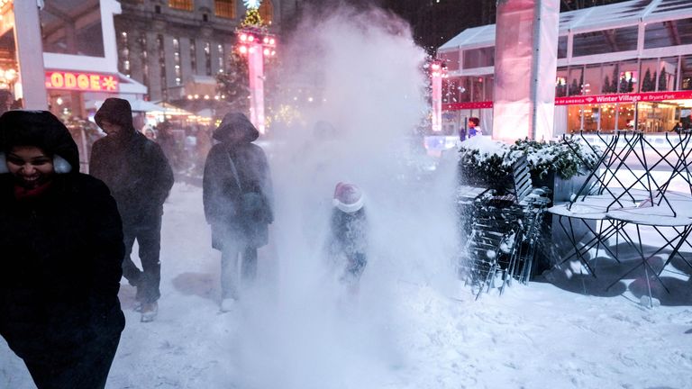 People are hit by snow from a snowplough at Bryant Park ice rink in New York City. Pic: Reuters