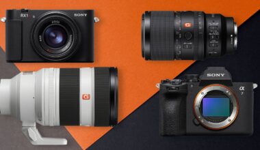Four Sony camera products on a black and orange background: two cameras (one compact, one mirrorless with no lens) and two interchangeable lenses, including a large telephoto lens and a shorter zoom lens.