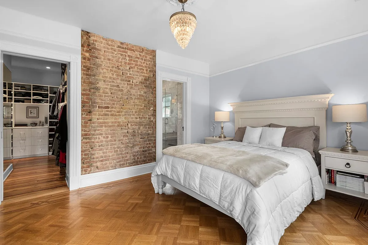 bedroom with wood floor, exposed brick on one wall