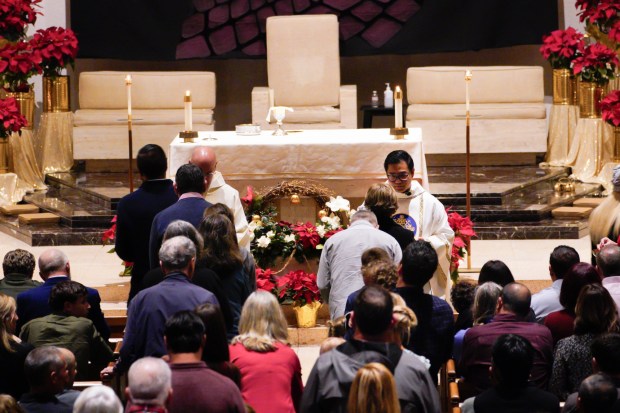 Father Brian Frulla (r) offers communion to parishioners during Christmas Eve Mass at St. Therese Catholic Church in the Del Cerro Community of San Diego.  Frulla is one of three men who were ordained in June and celebrated mass as new priests.  (Nelvin C. Cepeda / The San Diego Union-Tribune)