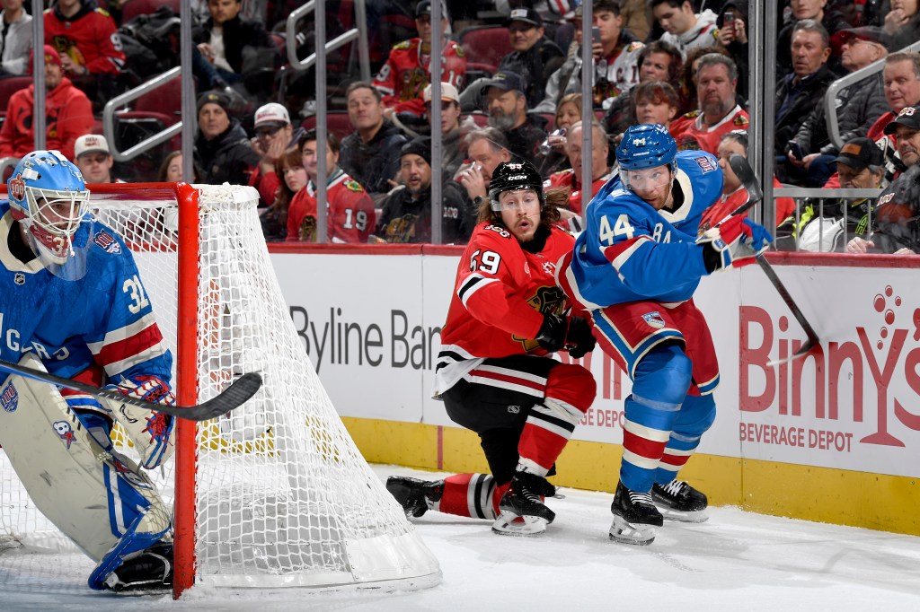 Hockey players Tyler Bertuzzi and Vladislav Gavrikov battling for the puck near the net.