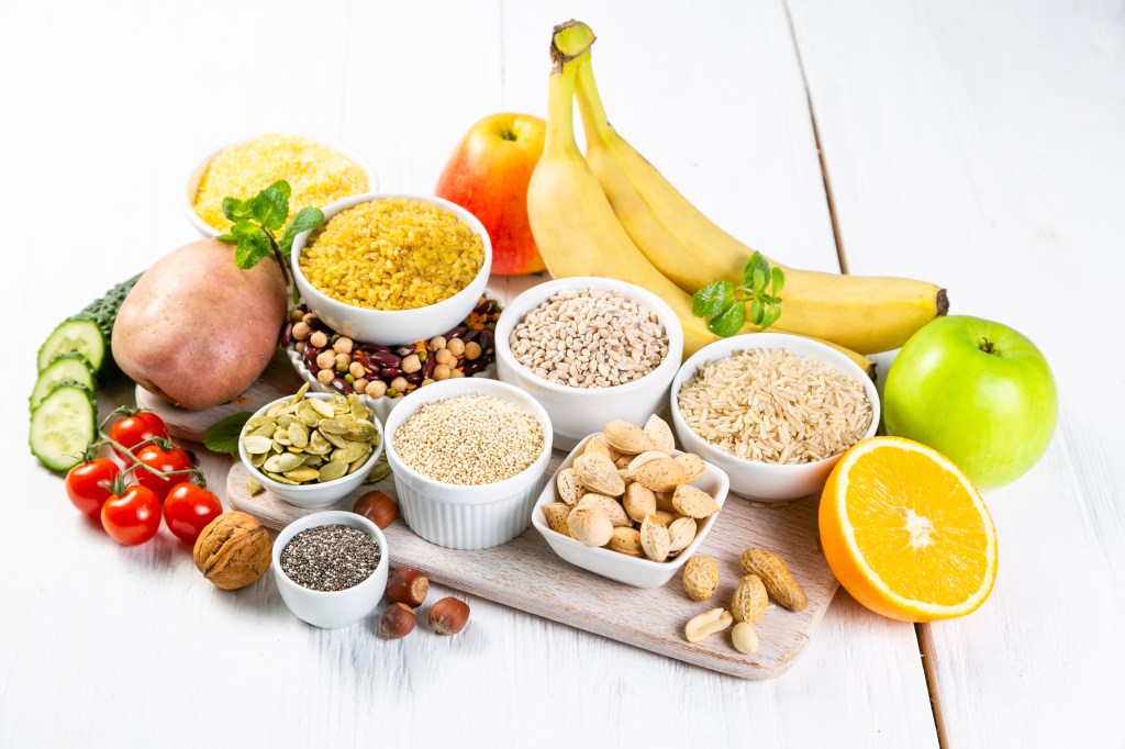 Selection of good carbohydrates, including vegetables, fruits, grains, legumes, nuts, and seeds.