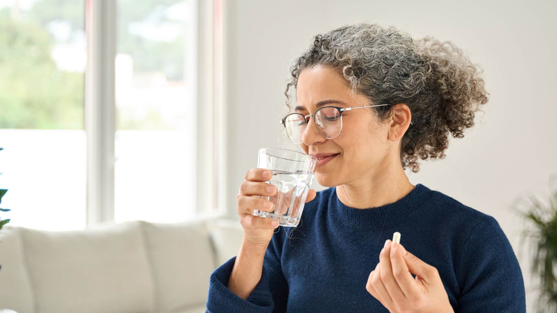 woman taking daily supplements with water