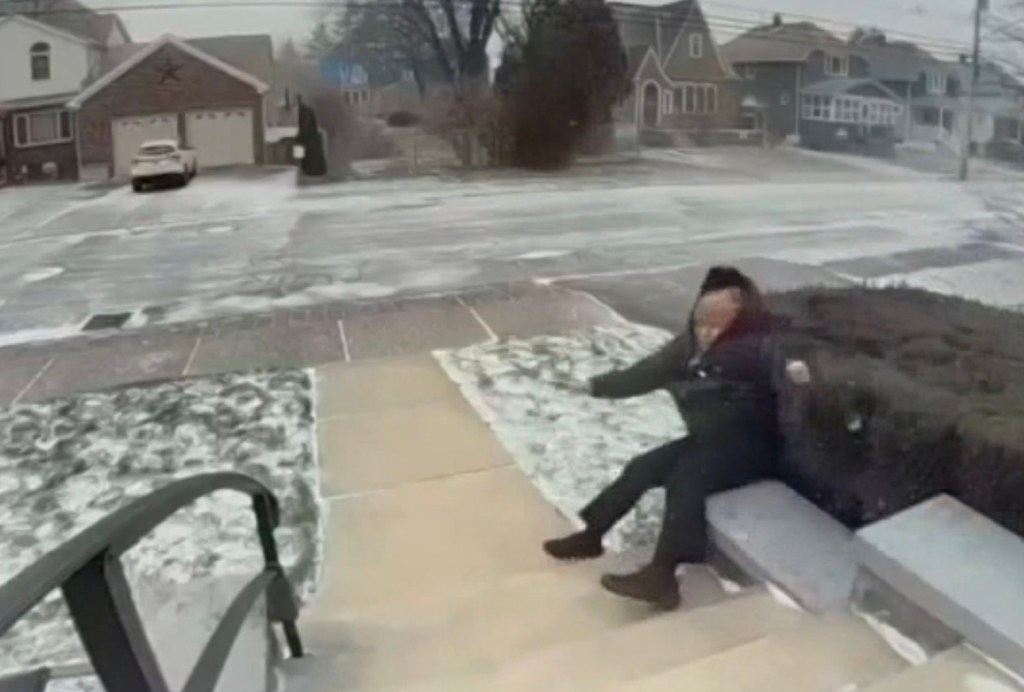 A person being blown over by strong wind while sitting on outdoor steps covered in snow.