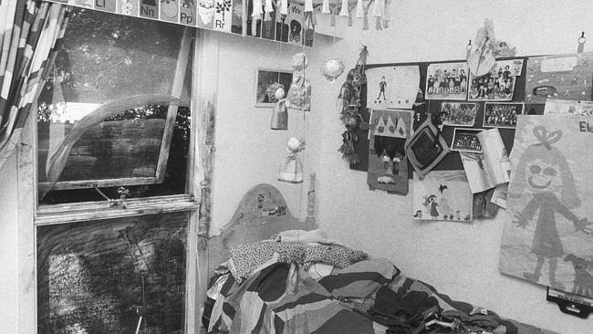 Black and white photo of a child's bedroom with flyscreen rolled back on a window next to a bed..