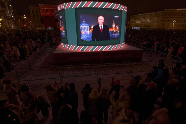 People watch Russian President Vladimir Putin's New Year's message a few minutes prior to the New Year at the Palace Square, in St. Petersburg, Russia, late Wednesday, Dec. 31, 2025. (AP Photo/Dmitri Lovetsky)