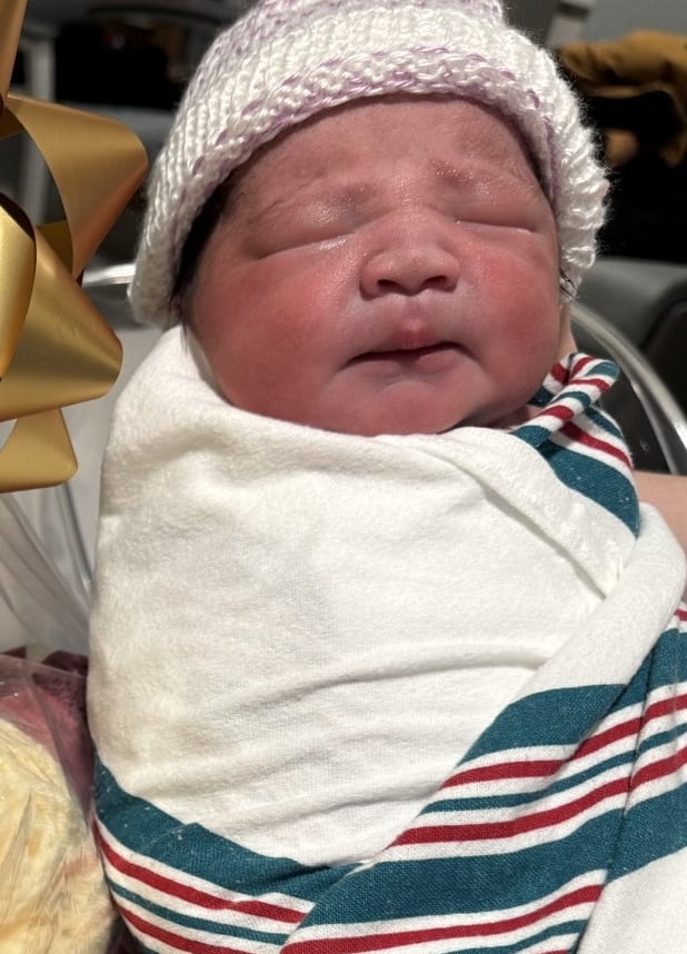 A baby is pictured beside a gift basket.