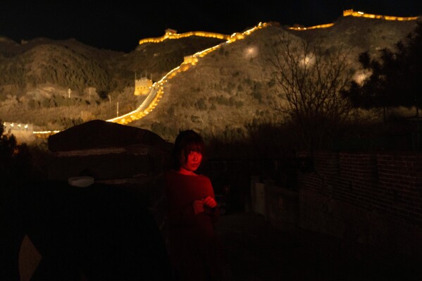 A woman stands for a photo by her friend before an event to ring in the new year at the Juyongguan Great Wall on the outskirts of Beijing, Dec. 31, 2025. (AP Photo/Ng Han Guan, File)