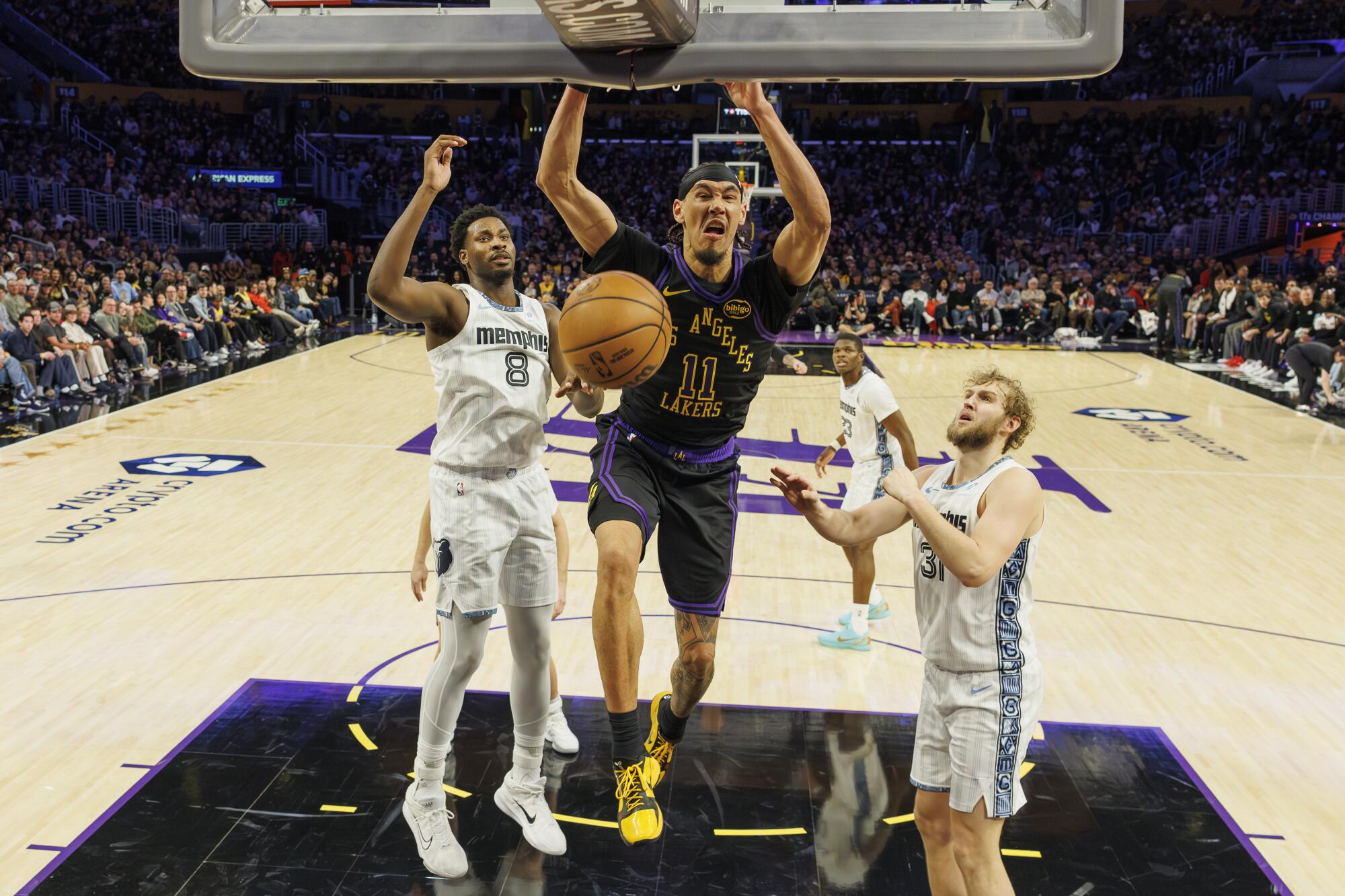 Lakers center Jaxson Hayes dunks over Memphis Grizzlies forward Jaren Jackson Jr. and center Jock Landale.