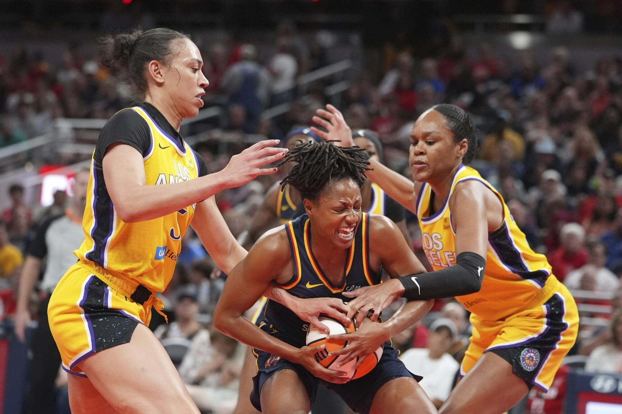 Fever forward Kelsey Mitchell, middle, drives to the basket between the Sparks' Dearica Hamby, left, and Azurá Stevens.