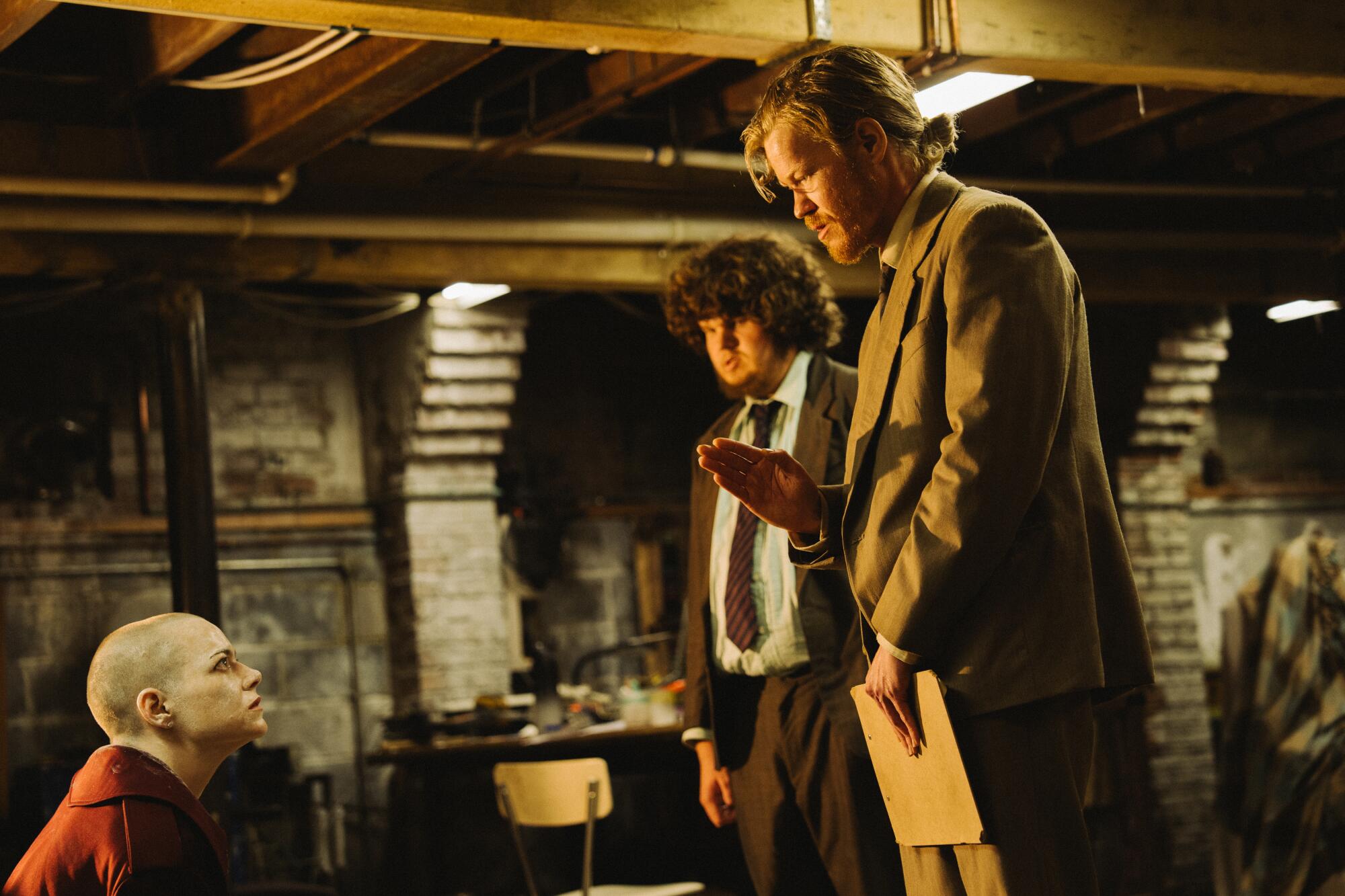 Three people have a tense discussion in a home's basement.