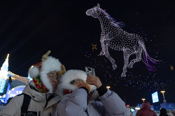 Visitors look at a drone swarm show at the annual Ice and Snow Festival held in Harbin in northeastern China's Heilongjiang province on Sunday, Jan. 4, 2026. (AP Photo/Ng Han Guan)