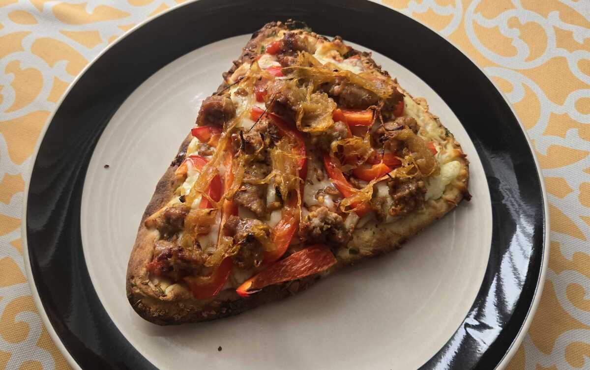 Naan pizza with sausage, peppers and caramelized onions.