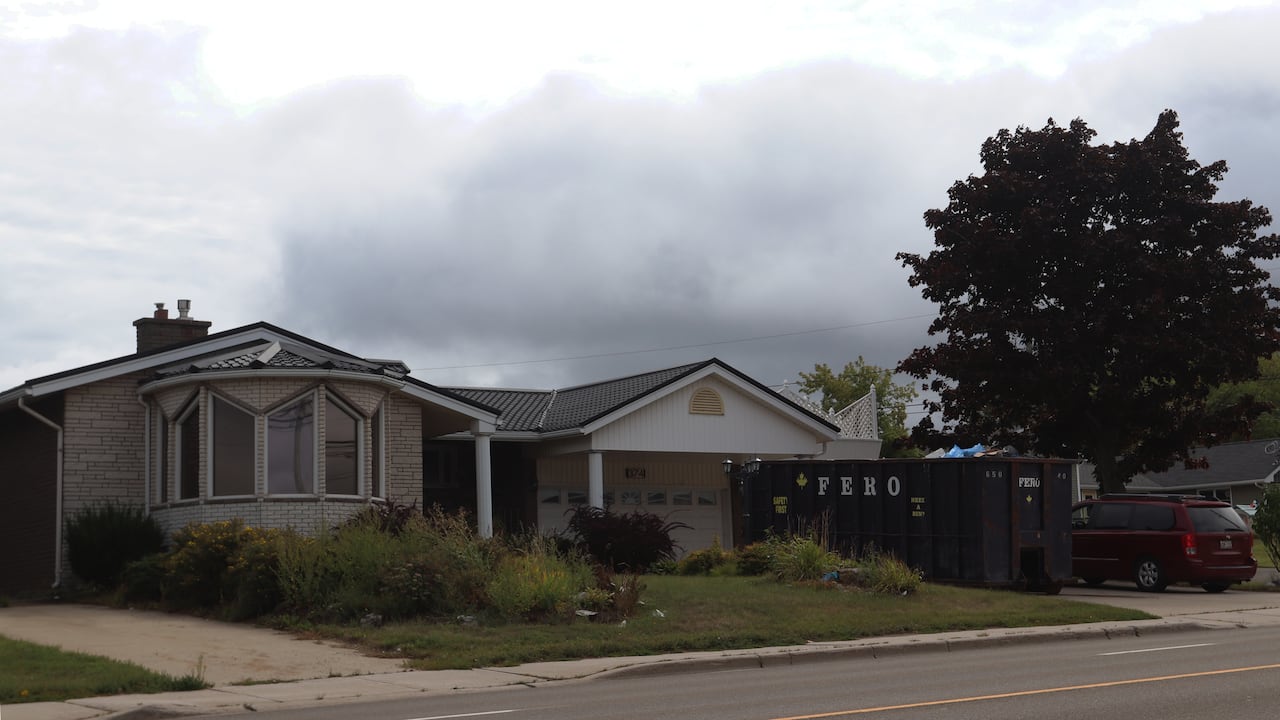 A one-storey house with a dumpster outside.
