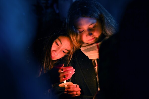 People hold candles during a vigil in Providence, R.I., for those injured or killed in the previous day's shooting on the campus of Brown University, Sunday, Dec. 14, 2025. (AP Photo/Steven Senne, File)