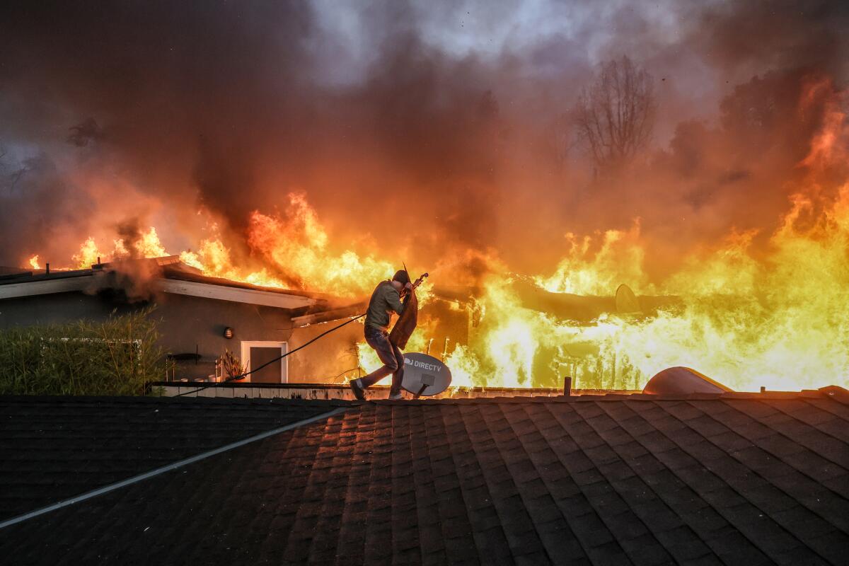 Steve Salinas shields from intense heat as he hoses down a neighbors rooftop