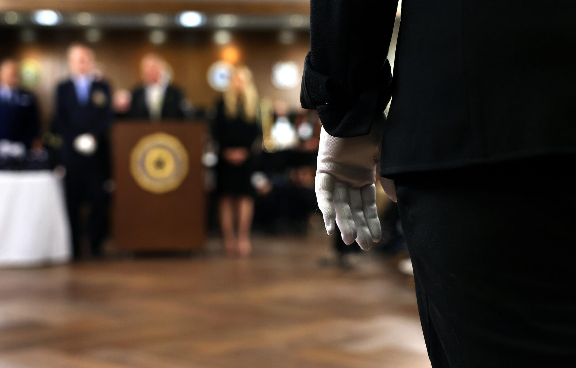 A person wearing a white glove stands at attention.