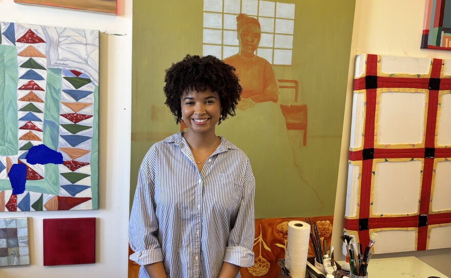 Emerging Artist, Eden DeLaVara, standing in front of her art in a studio at Liberty Station on Dec. 4th, 2025.