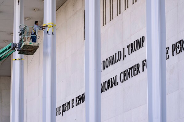 FILE - Workers add President Donald Trump's name to the John F. Kennedy Memorial Center for the Performing Arts after a Trump-appointed board voted to rename the institution, in Washington, Dec. 19, 2025. (AP Photo/J. Scott Applewhite)