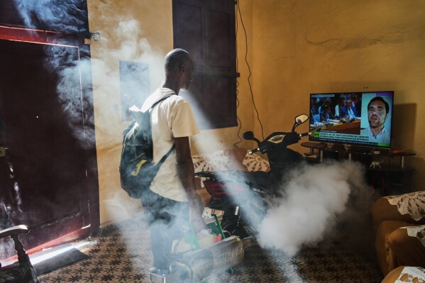 A mosquito control worker fumigates a home where a television plays a government television news report concerning the U.S. forces' capture of Venezuelan President Nicolas Maduro and his wife, in Old Havana, Cuba, Tuesday, Jan. 6, 2026. (AP Photo/Ramon Espinosa, File)