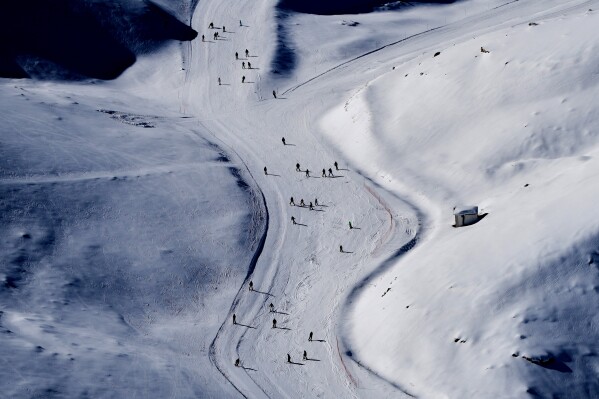 Skiers cast long shadows as they glide down a slope at the Mzaar-Kfardebian ski resort northeast of Beirut, Lebanon, Saturday, Jan. 3, 2026. (AP Photo/Hassan Ammar, File)