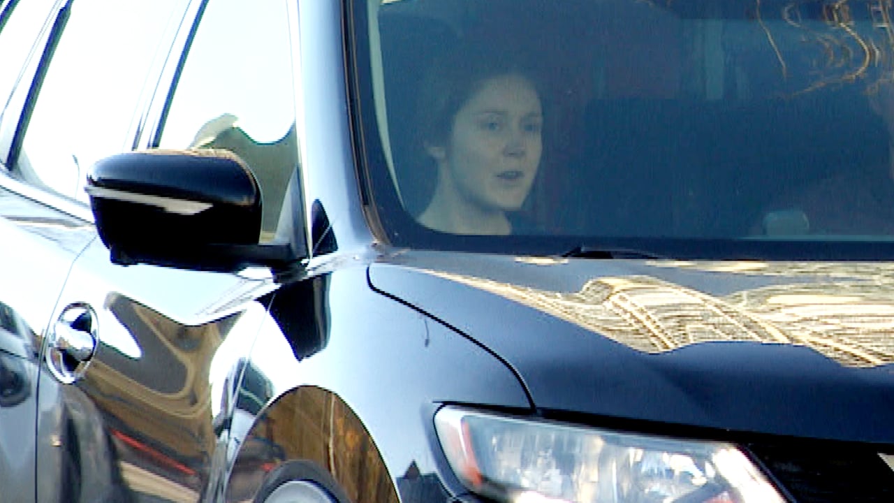 Woman sits in front seat of black car