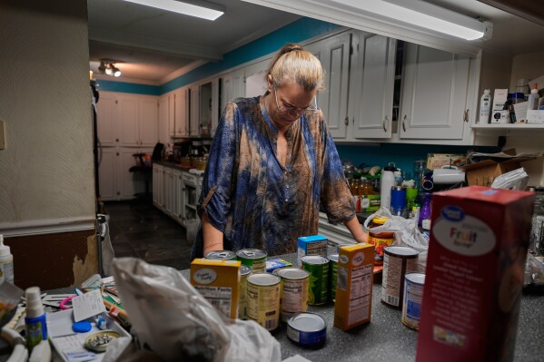 FILE - Goldie Getter, the wife of a civil service employee who was furloughed due to the government shutdown, unpacks groceries her husband received from a food bank in Gulfport, Miss., Nov. 3, 2025. (AP Photo/Gerald Herbert)
